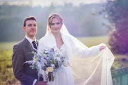A bride and groom posing for a photo in the Orchardleigh field.