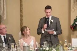 A bride and groom giving a speech at their wedding reception surrounded by the beautiful ambience of Orchardleigh House.