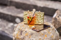 A golden purse, a glass of iced tea, and a smartphone placed on a lichen-covered rock at Orchardleigh House.