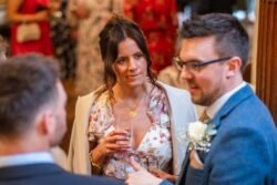 A woman and a man in formal attire conversing with another person at an Orchardleigh House Wedding.