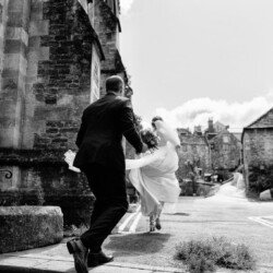 Wedding couple running through the street in Frome after their wedding at Rook Lane