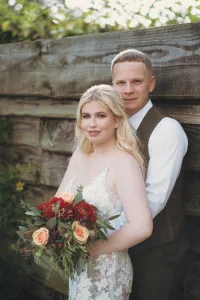 A bride and groom posing in front of a wooden fence.Priston Mill Wedding Photographer