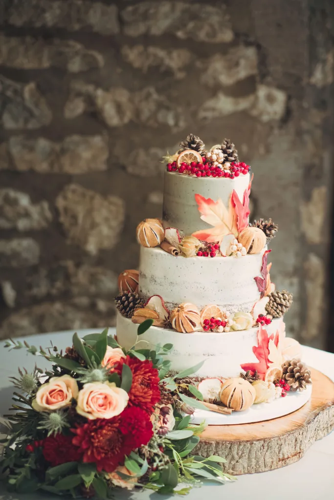 A three tier wedding cake is sitting on top of a tree stump.Priston Mill Wedding Photographer