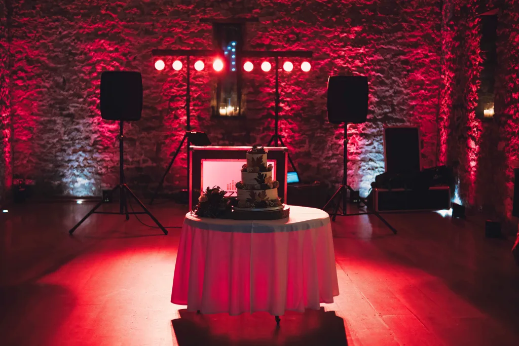 A table with a cake in front of red lights.Priston Mill Wedding Photographer
