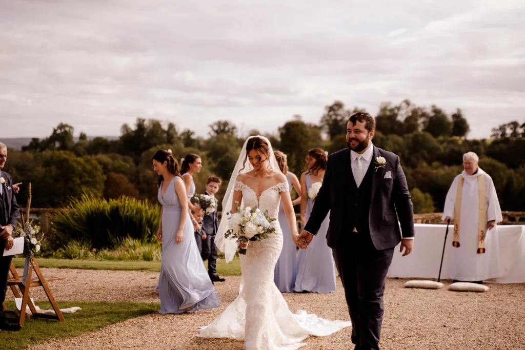 A bride and groom walking down the aisle at a wedding. Orchardleigh `House Weddings